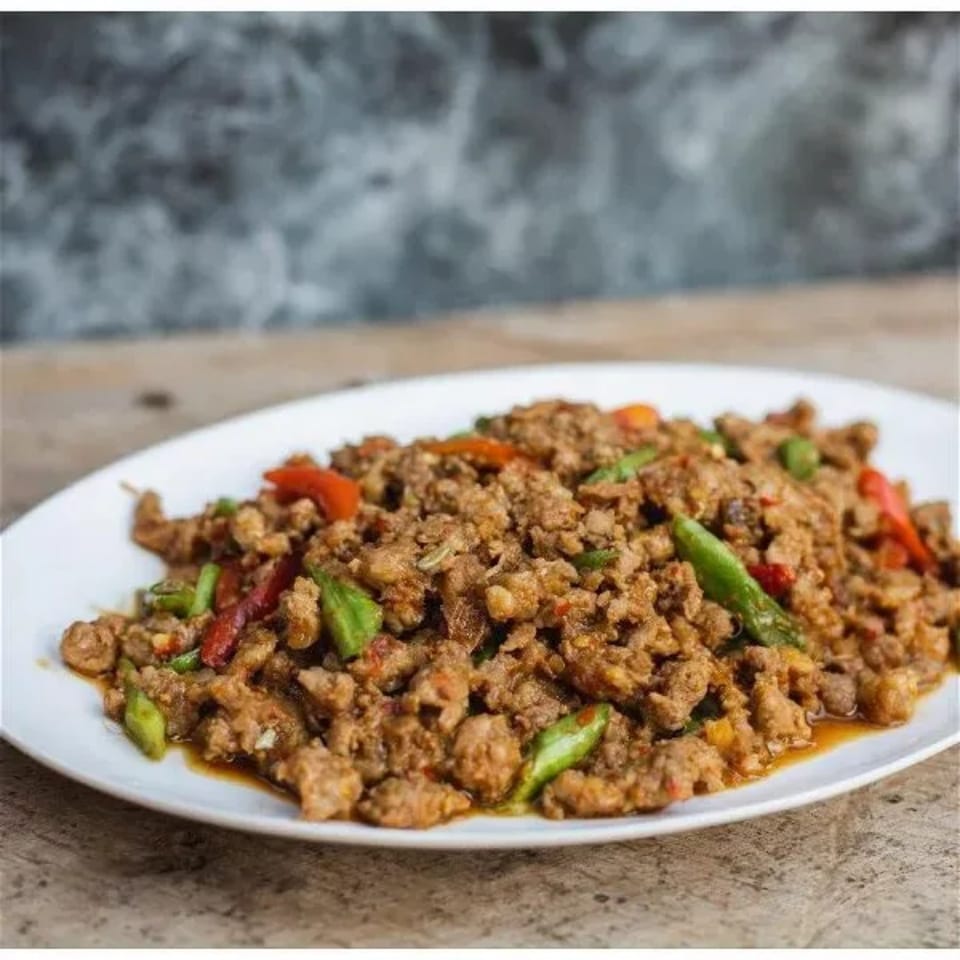 A white plate filled with savory minced meat, red and green peppers, and a rich sauce.